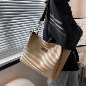 Detail of minimalist tote bag with gold ring hardware and logo plaque in light beige