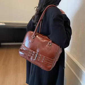 Borsa a spalla vintage marrone in ecopelle con fibbie indossata da una modella
