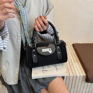 Detail of black Boston bag with suede panels, heart pendant, and metal rivet accents