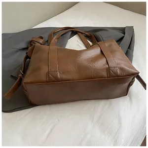 Detail view of brown PU leather tote bag with dual handles and adjustable shoulder strap