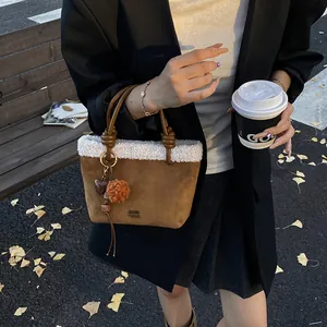 Detail der braunen Wildledertasche mit weißem Lammfellbesatz und Herzanhänger-Deko