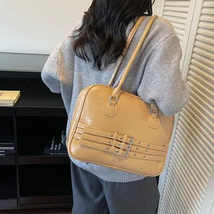 Dettaglio borsa a tracolla marrone chiaro con cinturini decorativi e fibbie argentate