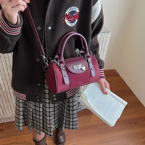 Detail showing the burgundy leather boston bag with heart charm and silver metal plate