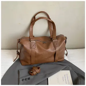 Detail of vintage brown travel tote bag showing PU leather texture and detachable shoulder strap