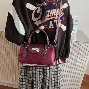 Detail of vintage burgundy boston bag with heart hardware worn as a crossbody