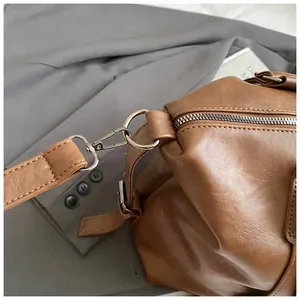 Detailed close-up of brown leather bag showing metallic hardware and premium texture