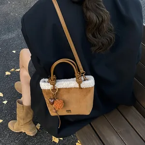 Detail der braunen Wildledertasche mit weißem Lammfellbesatz und Plüsch-Herzanhänger