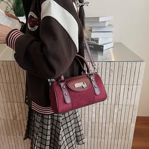 Detail of burgundy Boston bag with matte texture, leather trim and adjustable strap