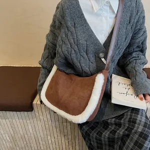 Detail of a brown suede underarm bag with white faux fur trim on a knit sweater outfit