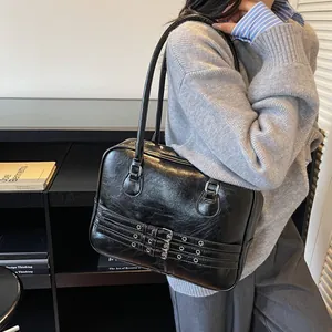 Dettaglio della borsa a spalla in PU nero con occhielli metallici vintage e trama lucida