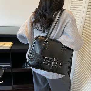 Dettaglio della borsa a spalla nera lucida con fibbie argentate e manici lunghi