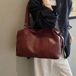 Detail of burgundy PU leather travel tote with wide shoulder strap and drawstring accents