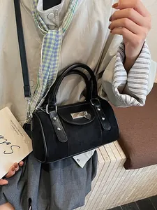 Chic black boston bag with silver rivets and heart pendant shown on model in retro style