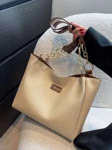 Fashionable beige and brown tote bag with leather straps and gold chain handles