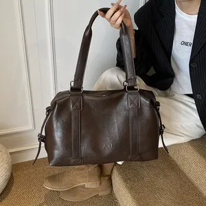 Detail of a large dark brown leather tote bag with reinforced stitching on the shoulder strap