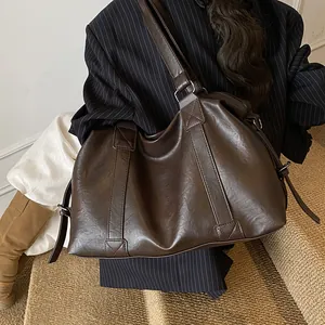 Detail view of large dark brown PU leather tote bag shown in a lifestyle model setting