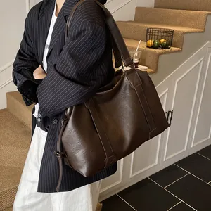 Close-up of dark brown tote bag featuring wide strap and cross-stitch detail