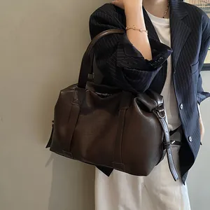 Detail of dark brown leather tote bag with sturdy straps and vintage texture on office blazer