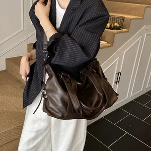 Detail of a large dark brown faux leather tote with adjustable strap and drawstring sides