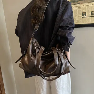 Detail of a large brown leather tote bag with silver buckles and adjustable shoulder strap