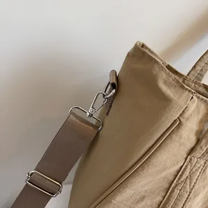 Detail of silver metal hook and durable fabric strap on khaki nylon tote bag