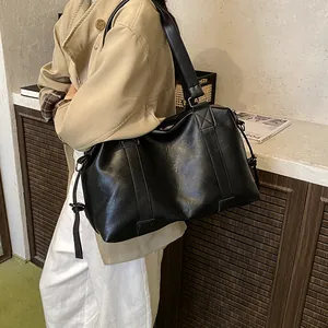 Detailed view of spacious black faux leather travel tote bag with glossy finish and wide straps