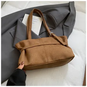Detail of brown faux suede tote bag with adjustable belt strap and silver buckle