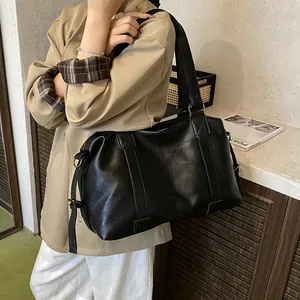 Close-up of black leather travel tote bag with reinforced handles and metallic hardware