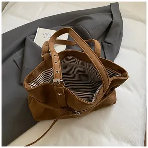 Detail of brown faux suede tote bag showing striped lining and interior zip pocket
