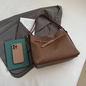 Detailed view of dark brown pleated tote bag with silver metal ring and leather handle