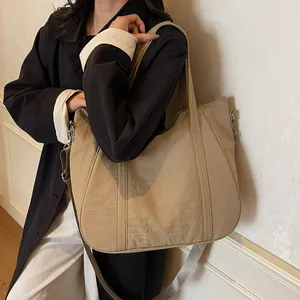 Khaki large capacity nylon tote bag with adjustable wide strap shown on shoulder