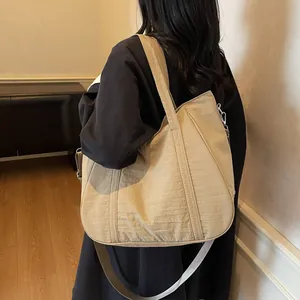 Close-up of lightweight pleated nylon tote bag with wide strap and grey woven crossbody strap