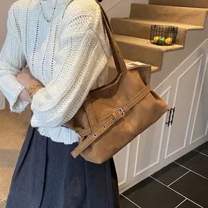 Detailed view of deep brown suede tote bag with metal buckle belt on interior stairs