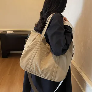 Detail of a large beige nylon tote bag showing its reinforced straps and soft texture