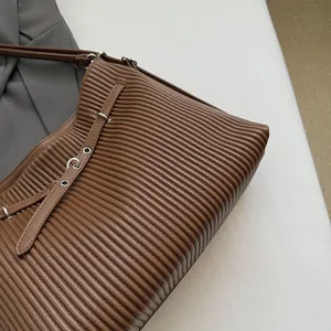 Close-up of coffee brown tote bag featuring unique pleated texture and silver eyelets
