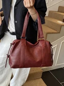 Minimalist large burgundy tote bag with leather texture shown on shoulder of a model