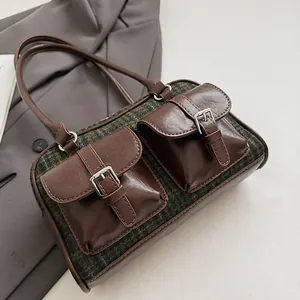 Detail of vintage plaid Boston bag with leather trim and decorative buckle front pockets