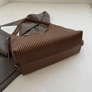 Detail of brown pleated leather shoulder bag with silver hardware and textured finish
