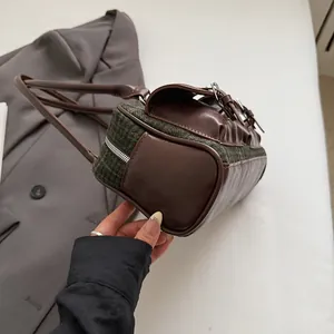 Detail of vintage Boston bag showing green tweed fabric and brown leather stitching