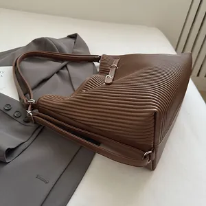 Detail of dark brown tote bag featuring vertical pleated texture and leather straps