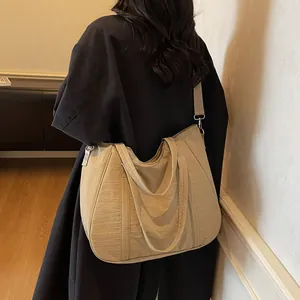 Rear view of a large khaki nylon tote bag with adjustable strap on a black coat