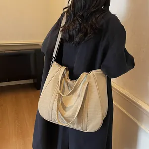 Detail of a large khaki nylon tote bag showing double handles and adjustable strap