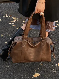 Large brown PU leather travel tote bag with top handles shown on outdoor leaves pavement