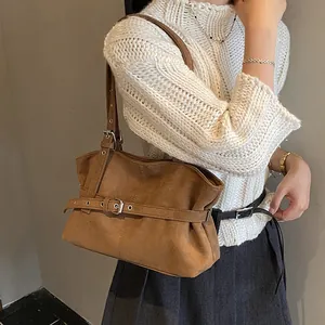 Detail of adjustable silver buckle and suede texture on brown shoulder tote bag