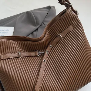 Detail of dark brown leather pleated bag featuring metallic buckle and hardware accents