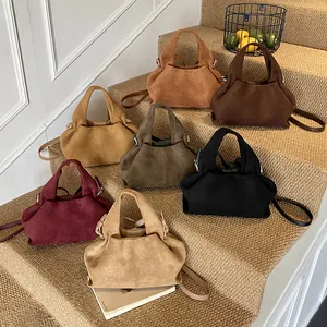 Collection of seven suede crossbody bags in earthy tones displayed on a staircase detail