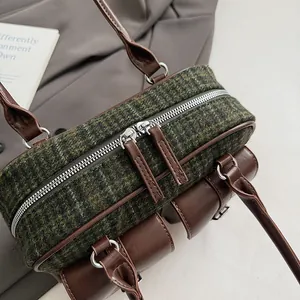 Detail view of green tweed Boston bag with dark brown leather straps and silver zippers