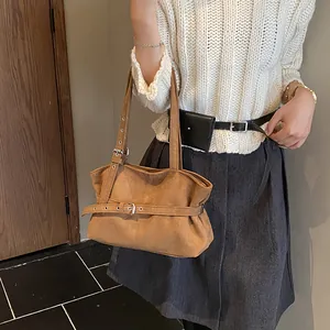 Detail of the vintage suede tote with decorative belt buckle and metallic eyelets