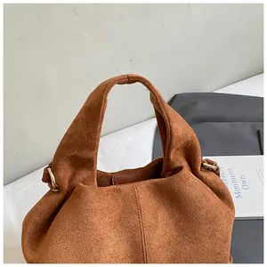 Detailed macro view of caramel suede tote bag fabric with metallic ring handle attachment