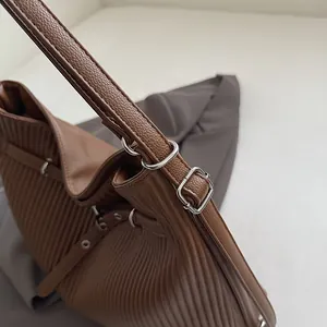 Detail shot of pleated caramel brown PU leather bag with silver metal ring and strap buckle